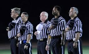 Referees standing at attention during the National Anthem.