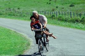 Granddad riding Pai to school on  his bicycle. 